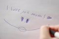 moms day . I love you mom inscription on a white sheet and a childs hand with a pen.Holiday of all mothers Royalty Free Stock Photo