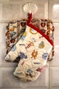 Moms kitchen - a potholder and an oven mitt hang from a plastic shell-shaped hanger on tile in a homey kitchen - closeup