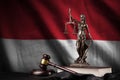 Monaco flag with statue of lady justice, constitution and judge hammer on black drapery. Concept of judgement and guilt