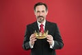 Monarchy attribute. Monarchy family traditions. Man bearded guy in suit hold golden crown symbol of monarchy. Become Royalty Free Stock Photo