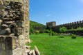 Monastery courtyard. Part of the stone wall of the church. External wall with loopholes. Gravestones are visible. Daylight, blue Royalty Free Stock Photo