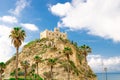 Monastery Sanctuary church of Santa Maria dell Isola on top of rock of Tyrrhenian Sea and green palm trees, blue sky with white Royalty Free Stock Photo