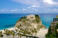 Monastery Sanctuary church of Santa Maria dell Isola on top of rock Tyrrhenian Sea and green palm trees, blue sky white clouds in Royalty Free Stock Photo