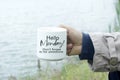 Monday inspirational quote - Hello Monday. Do not forget to be awesome. Person holding a cup of morning coffee in hand with text.