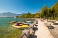 Mondsee lake, Austria. Wooden piers and boats. Benches under trees on the promenade.