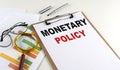 MONETARY POLICY text on clipboard with chart on white background, business concept