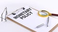 MONETARY POLICY text on clipboard on white background, business concept