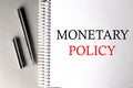 MONETARY POLICY text on a notebook with pen on grey background