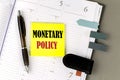 MONETARY POLICY word on the yellow sticky with office tools on daily planner