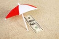 Money american hundred dollar bill unter sunshade on beach sand