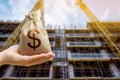 A money bag against the background of a building under construction. The concept of investing money in the construction and