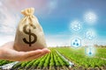 Money bag on the background of agricultural crops in the hand of the farmer. Agricultural startups. Profit from agribusiness. Royalty Free Stock Photo