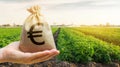 Money bag on the background of agricultural crops in the hand of the farmer. Agricultural startups. Profit from agribusiness. Royalty Free Stock Photo