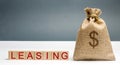 Money bag and blocks with the word Leasing. A lease is a contractual arrangement calling for the lessee to pay the lessor for use Royalty Free Stock Photo