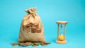 Money bag with coins and a clock / hourglass. Time management and distribution. Concept of saving money. Planning work. Business Royalty Free Stock Photo