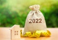 Money bag 2022 and a wooden house. Real estate concept. Family budget planning. Investments, plans, savings. Mortgage and mortgage Royalty Free Stock Photo