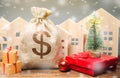 Money bag, wooden houses, Christmas tree and gifts. Holiday discounts. Christmas sale of real estate. New Year discounts for Royalty Free Stock Photo