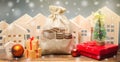 Money bag, wooden houses, Christmas tree and gifts. Christmas Sale of Real Estate. New Year discounts for buying housing. Purchase Royalty Free Stock Photo