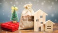 Money bag, wooden houses, Christmas tree and gifts. Christmas Sale of Real Estate. New Year discounts for buying housing. Purchase Royalty Free Stock Photo