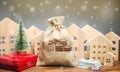 Money bag, wooden houses, Christmas tree and gifts. Christmas Sale of Real Estate. New Year discounts for buying housing. Purchase Royalty Free Stock Photo