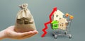 Money bag, wooden houses in a shopping cart and red arrow up. Real estate price growth concept. High demand for housing. Building Royalty Free Stock Photo