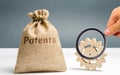 Money bag with the word Patents and a wooden gear. Registration of patents and copyright compliance. Licensing technology and