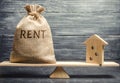 Money bag with the word Rent and a wooden house on the scales. The concept of payment for rental housing. Debt repayment. To Royalty Free Stock Photo