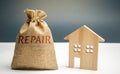 Money bag with the word repair and a wooden house. Saving and accumulation of money to repair. Concept of a new house, apartment Royalty Free Stock Photo
