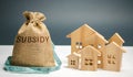 Money bag with the word Subsidy and wooden houses. Financial aid, support to the population. Cash grants, interest-free loans. Tax Royalty Free Stock Photo