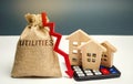Money bag with the word Utilities and an arrow down and wooden houses on the calculator. Reduced prices for utilities. Low prices Royalty Free Stock Photo