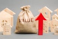 A money bag with the word Value, wooden houses and an up arrow. Concept of real estate market growth. High rental and mortgage Royalty Free Stock Photo