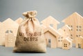 Money bag with the words Utility bill debts and wooden houses. Fines and penalties for failure to pay the debt for electricity and
