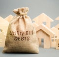 Money bag with the words Utility bill debts and wooden houses. Fines and penalties for failure to pay the debt for electricity and Royalty Free Stock Photo