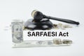 Money banknotes, judge gavel and coins over white background written with SARFAESI ACT Royalty Free Stock Photo