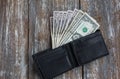 Money in the black leather wallet lying on rustic wooden background. Dollars for making purchases and byung things. Shopping time Royalty Free Stock Photo