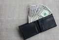 Money in the black leather wallet lying on the table cloth. Dollars for making purchases and byung things. Shopping time Royalty Free Stock Photo