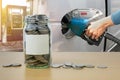 Money bottle with coins, Hand holding Fuel nozzle pouring Royalty Free Stock Photo