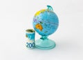 A money box made in the form of a globe, the planet Earth with a money slot at the top stands near a rolled up and held together s Royalty Free Stock Photo