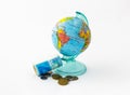 A money box made in the form of a globe, the planet Earth with a money slot at the top stands near a rolled up and held together s Royalty Free Stock Photo