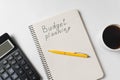 Money budget planning. Handwritten text. Notebook with calculator and Cup of coffee on white background