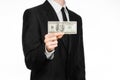 Money and business theme: a man in a black suit holding a bill of 100 dollars and features a hand gesture on an isolated white bac Royalty Free Stock Photo