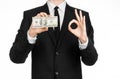 Money and business theme: a man in a black suit holding a bill of 100 dollars and features a hand gesture on an isolated white bac Royalty Free Stock Photo