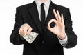 Money and business theme: a man in a black suit holding a bill of 100 dollars and features a hand gesture on an isolated white bac Royalty Free Stock Photo