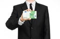 Money and business theme: a man in a black suit holding a bill of 100 euros and shows a hand gesture on an isolated white backgrou Royalty Free Stock Photo