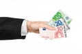 Money and business topic: hand in a black suit holding banknotes 10,20 and 100 euro on white isolated background in studio Royalty Free Stock Photo