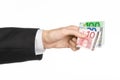 Money and business topic: hand in a black suit holding banknotes 10,20 and 100 euro on white isolated background in studio Royalty Free Stock Photo