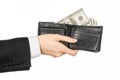 Money and business topic: hand in a black suit holding a wallet with dollar banknotes isolated on white background in studioMoney Royalty Free Stock Photo