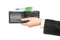 Money and business topic: hand in a black suit holding a wallet with 100 euro banknotes isolated on white background in studio Royalty Free Stock Photo