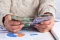 Money from Canada. Dollars. Retired woman holding bill on desk office