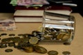 money and coins with books and a thrown jar of glass